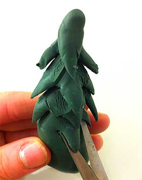 Further image of the Fimo clay, being cut and shaped as a Christmas tree